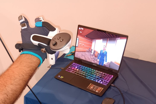 Laptop on table with hand above it wearing an XR application